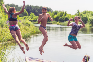Photograph of three children having fun jumping into a lake